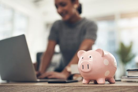 Finance, banking and saving money with piggybank, investing and planning while working on a laptop in an office at work. Managing and growth of budget for insurance, investment and retirement