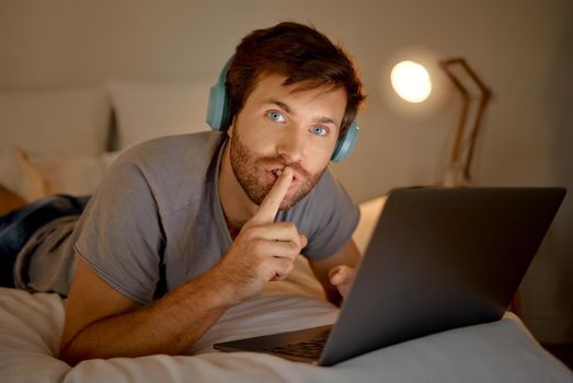 Laptop, portrait and quiet hand gesture from man trying to focus. Insomnia or workaholic reading emails at night in his bedroom. Silence expression from person for silent environment while working.