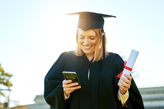 The quickest way to tell everyone about her big day. student using her cellphone on graduation day.
