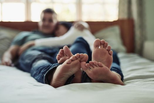 I love it when your feet touches mine. a couples feet as they lay on bed.