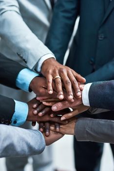 Teamwork gives us the strength to succeed. Closeup shot of a group of businesspeople joining their hands together in unity.