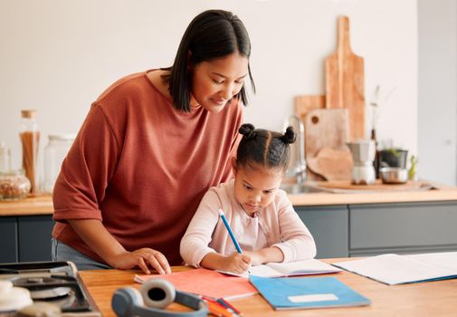 Mother teaching daughter, doing homework at kitchen table at home, bonding while learning together. Loving parent helping her child with a school project or task. Autistic child enjoying homeschool