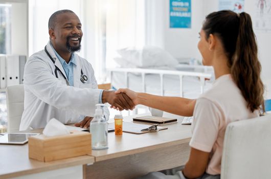 Healthcare, insurance and handshake between a doctor and patient consulting in an office, discussing a treatment plan. Happy woman smiling, satisfied with expert advice from health care professional