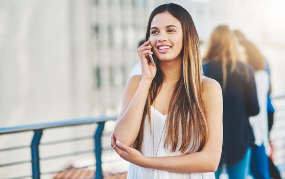 No distance is too great. an attractive young woman making a phone call while standing outside.