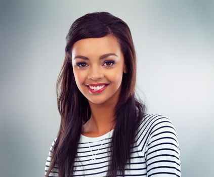 Take every chance to smile. a young woman posing against a grey background.