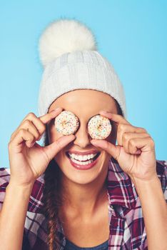 Have sweet dreams. a young woman covering her eyes with cookies against a colorful background.
