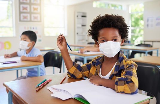 Child or student in class during covid, wearing a mask for hygiene and protection from coronavirus flu. Portrait kindergarten, preschool or elementary school boy sitting in a classroom ready to learn