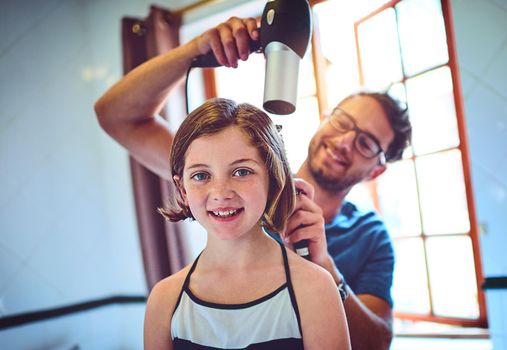 Dads my personal and favourite stylist. a father blowdrying his little daughters hair at home.