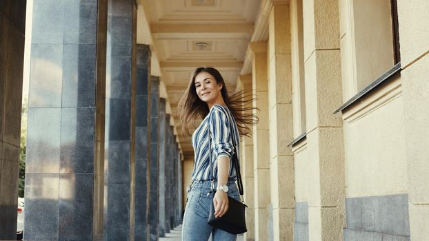 Street Style Outdoors Portrait of Cute Girl. Fashion Woman Smiling. She wearing Print Shirt, Jeans, Bag. Happy Lifestyle
