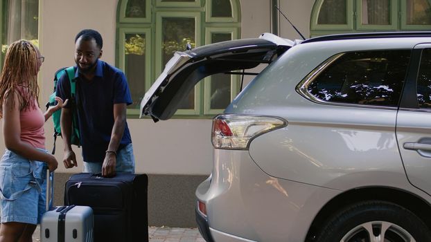 African american couple loading voyage luggage in car