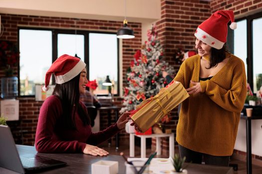 Asian woman receiving christmas present from coworker
