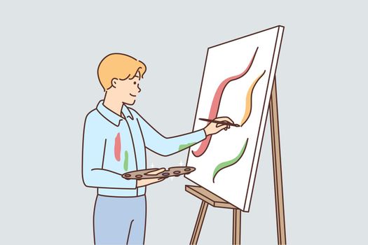 Young man drawing on easel