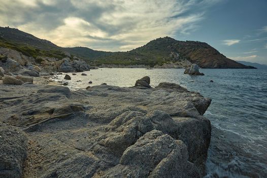 The rocks of the Mediterranean beach at sunset.