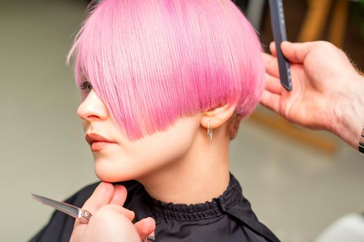 Hairdresser makes short pink hairstyle