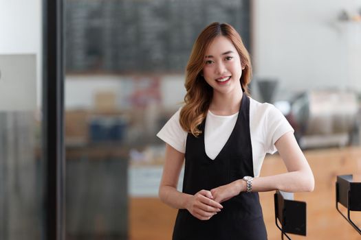 Beautiful Asian women Barista smiling at her cafe waiting for customer