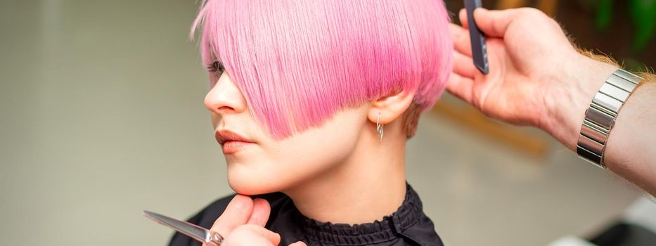 Hairdresser makes short pink hairstyle