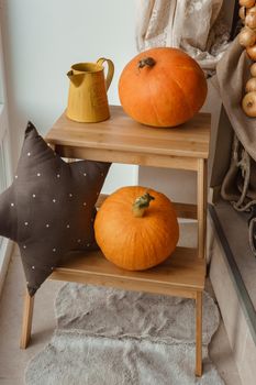 Autumn interior in a photo studio, with pumpkins, a vase and a wooden stool