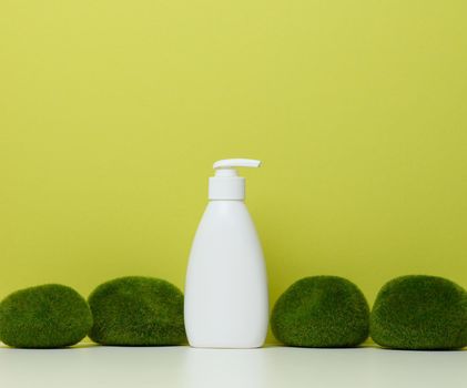 White plastic bottle with pump on a green background. Containers for cosmetics 