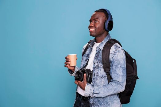 Smiling young man with professional camera and backpack going on holiday trip