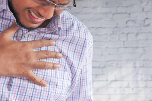 young man suffering pain in heart and holding chest with hand