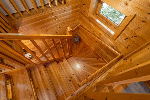 Upward view of wooden stairs and handrail in country house.