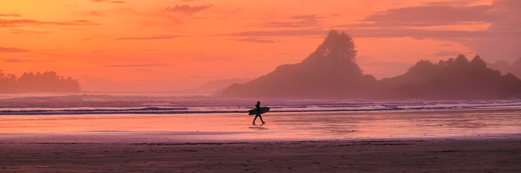Tofino Vancouver Island Pacific rim coast, surfers with board during sunset at the beach