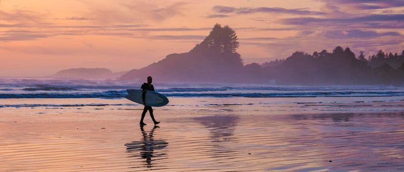 Tofino Vancouver Island Pacific rim coast, surfers with board during sunset at the beach