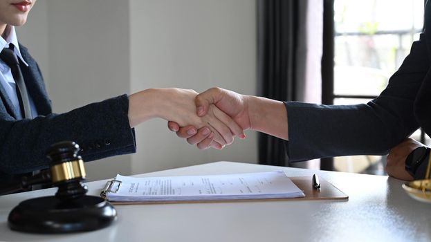Shot of lawyer or attorney shaking hands with clients after a contract agreement. Lawyer, justice and law and attorney concept