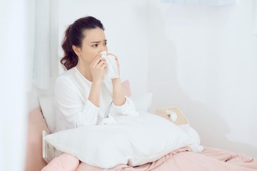 Sick woman with headache sitting under the blanket.