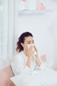 Asian woman feeling unwell and sneeze on bed