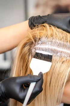 Hairdresser dyeing blonde hair roots