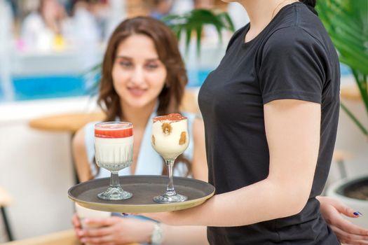 Waitress carrying tray with desserts