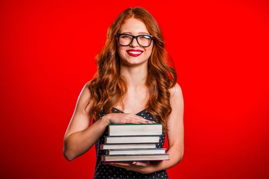 European student on red background in studio holds stack of university books