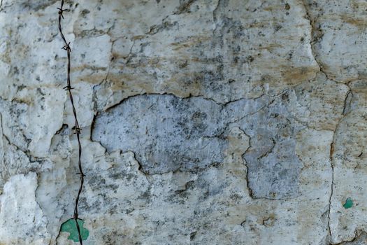 bottom of a chipped wall with barbed wire