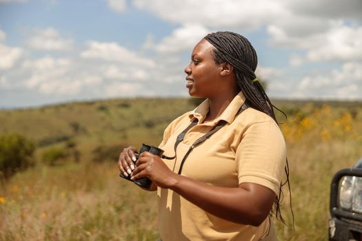 Female tour guide searching the landscape for wildlife in Africa