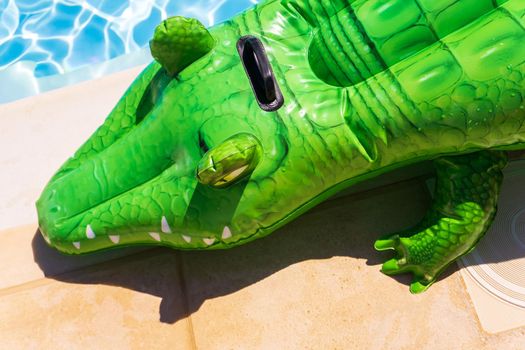 Inflatable crocodile on the side of the pool on a sunny day