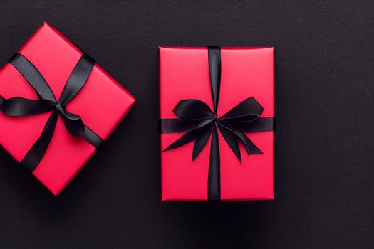 3D Render of red color gift box with black ribbon isolated against black background and Christmas decorations, top view design