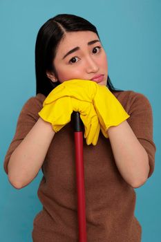 Depressed tired asian housewife holding on brush stick
