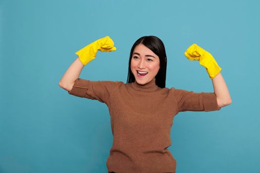 Excited happy and smiling asian housekeeping raising arms and showing biceps