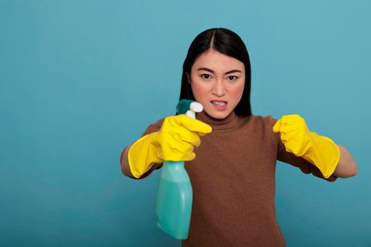 Excited energetic asian young housekeeper detergent sprayer standing in fight pose