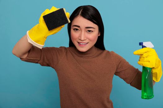 Pleased happy and joyful asian young woman holding a sponge