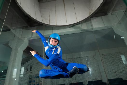 A man in overalls and a protective helmet enjoys flying in a wind tunnel. Free fall simulator