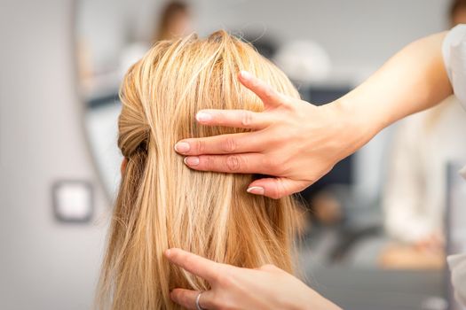Female hairdresser styling blonde hair