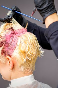 Hairdresser's hands applying pink dye