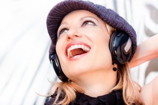 Blonde lady listening to the music with a pair of headphones