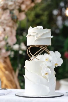White wedding cake with flowers. Wedding cake on the background of the wedding arch