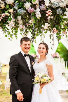 Wedding couple under the flower arch at the wedding ceremony