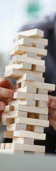 Young man removing wooden blocks from toy tower closeup