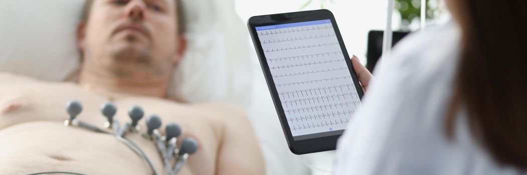 Doctor taking cardiogram to patient on couch in clinic closeup