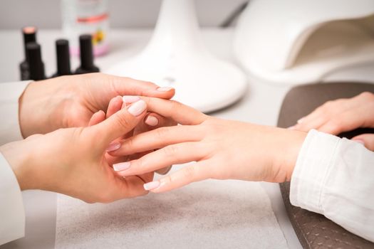 Manicurist is massaging female fingers